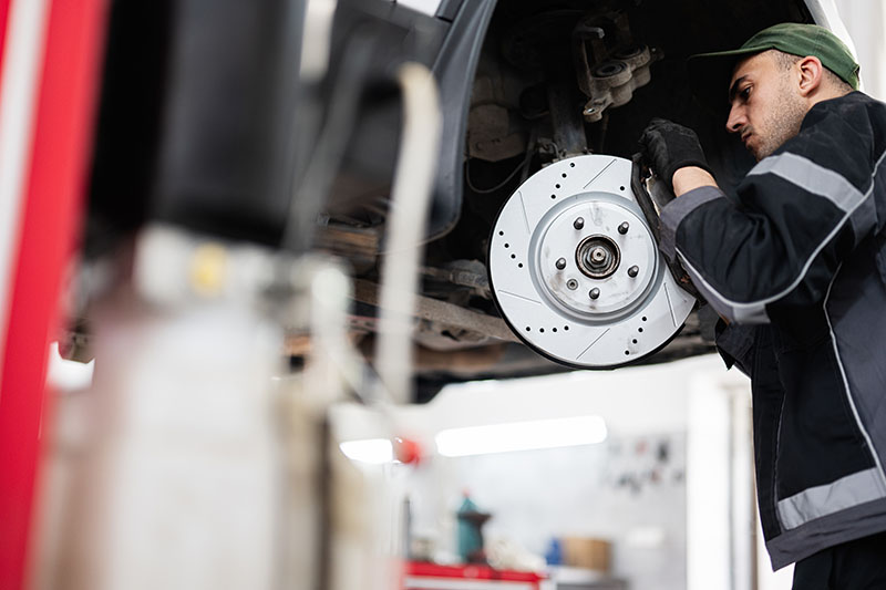 Technician performing brake checks at an auto repair shop.