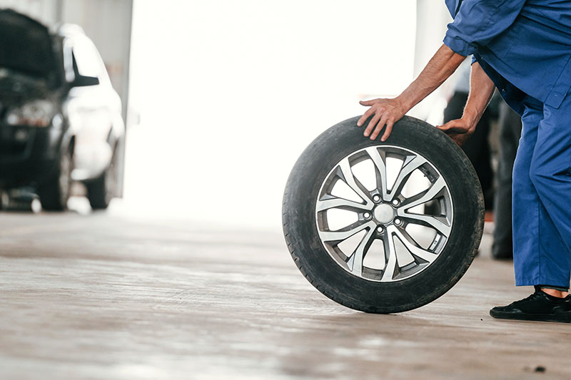 A technician at a tire shop handling a car tire for replacement.