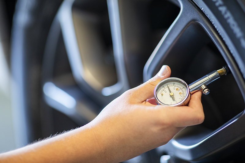 Hand using a PSI gauge to check tire pressure during a PSI service.