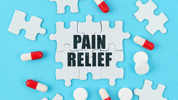 The words “pain relief” are seen written on white puzzle pieces, surrounded by red and white pills and white puzzle pieces alongside a light blue background. 