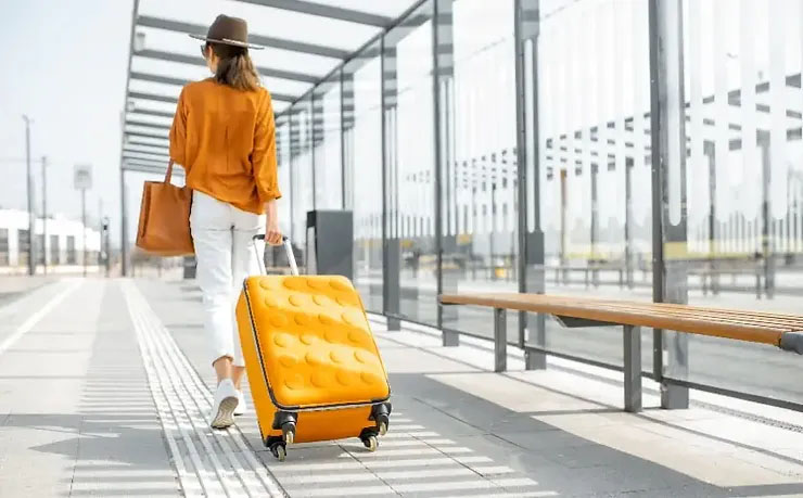 A woman walking down the street with her luggage.
