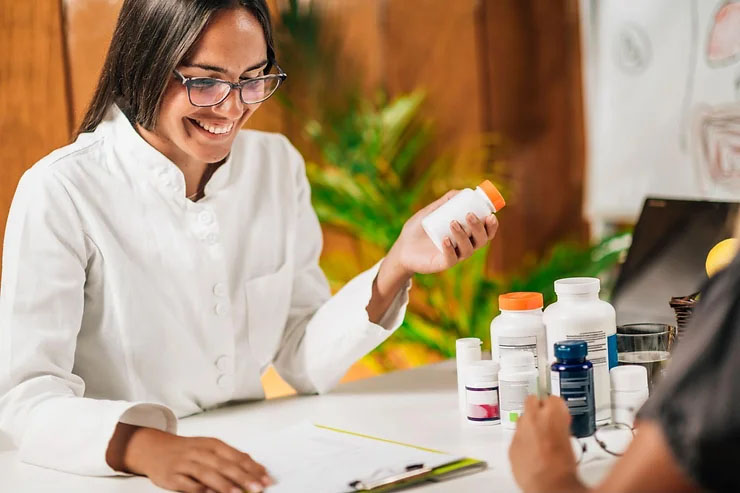 A female medical practitioner holds a bottle of prescribed medicine while looking at a client chart.