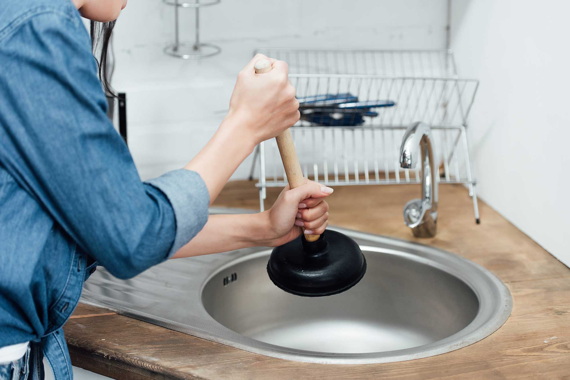 partial-view-of-woman-in-denim-shirt-using-plunger