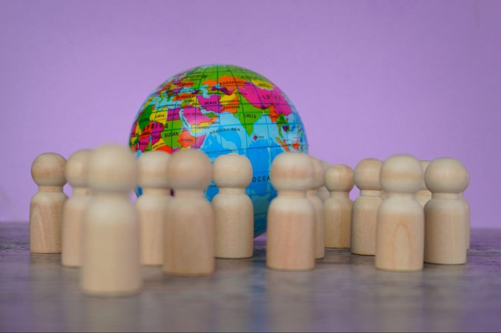 Wooden figures surrounding a globe.